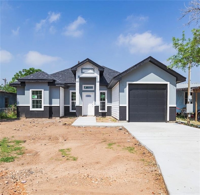 view of front of home featuring an attached garage, roof with shingles, and driveway
