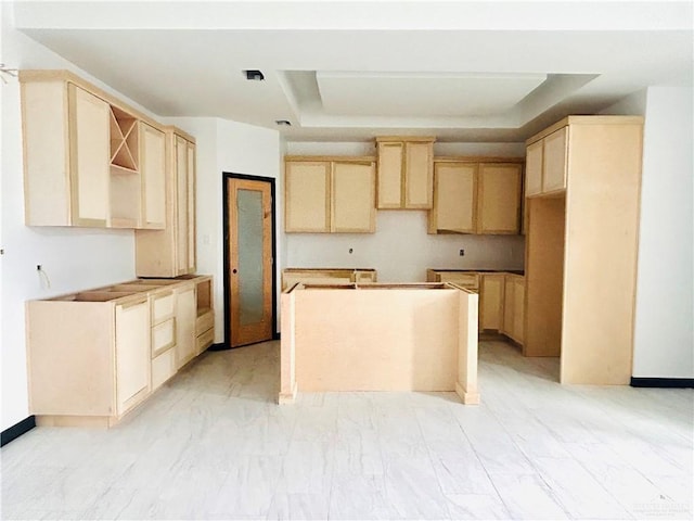 kitchen featuring light brown cabinets, marble finish floor, a kitchen island, and a raised ceiling