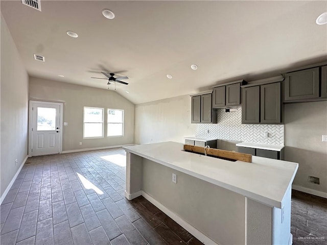 kitchen with tasteful backsplash, baseboards, a ceiling fan, and lofted ceiling
