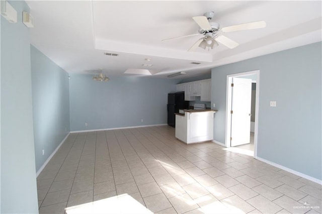 unfurnished living room featuring ceiling fan, a raised ceiling, and light tile patterned floors