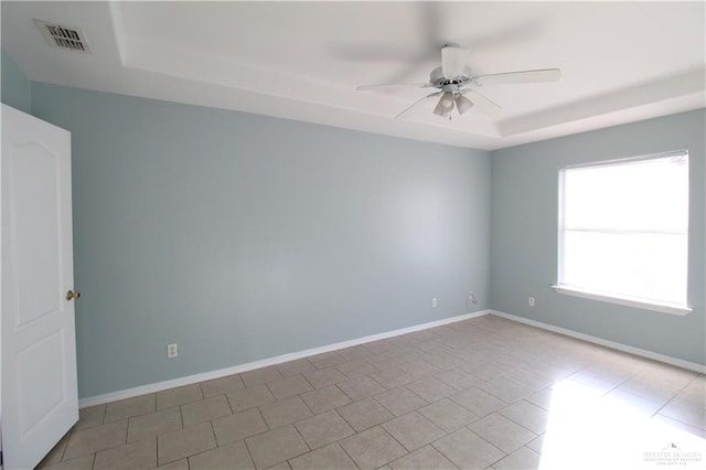 tiled spare room featuring ceiling fan and a raised ceiling