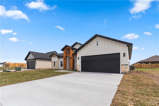 519 Oriole Dr, Los Fresnos, TX 78566 - view of front facade with fence, central AC unit, concrete driveway, a garage, and stone siding