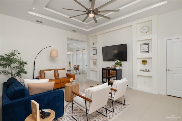 living room with built in shelves, a tray ceiling, light tile patterned floors, and ceiling fan