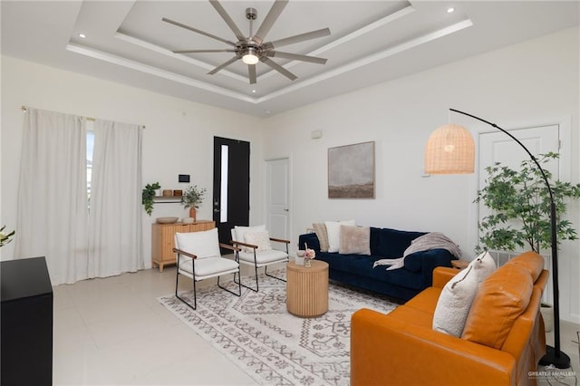 living room with ceiling fan, a raised ceiling, and light tile patterned floors