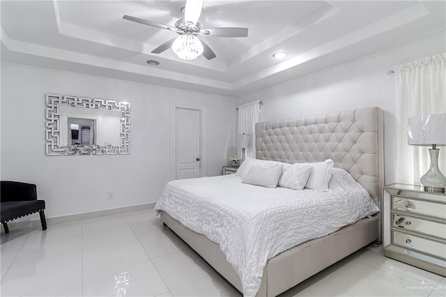 tiled bedroom with ceiling fan and a tray ceiling