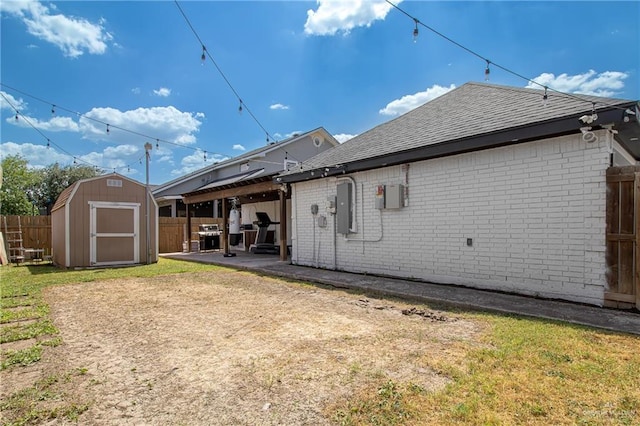 rear view of property with a patio area, a storage shed, and a yard