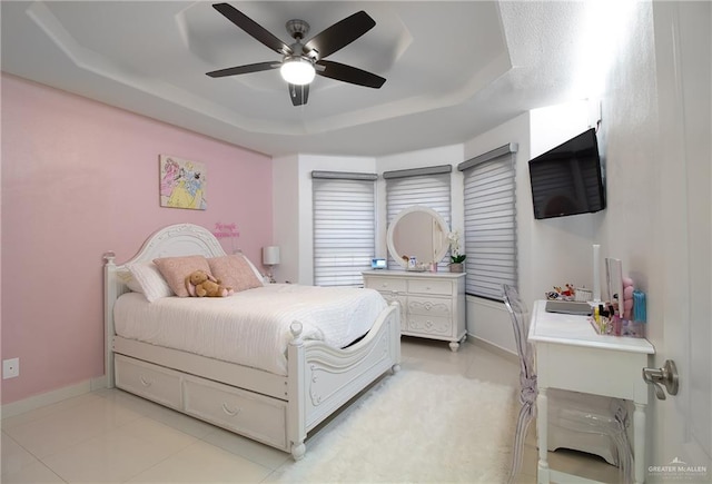 tiled bedroom featuring a tray ceiling and ceiling fan