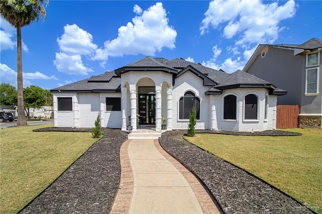 view of front facade featuring a front yard and solar panels