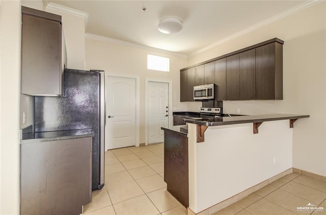 kitchen featuring light tile patterned flooring, a breakfast bar area, dark brown cabinets, ornamental molding, and kitchen peninsula