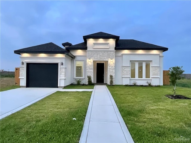 prairie-style home featuring an attached garage, stone siding, concrete driveway, stucco siding, and a front yard