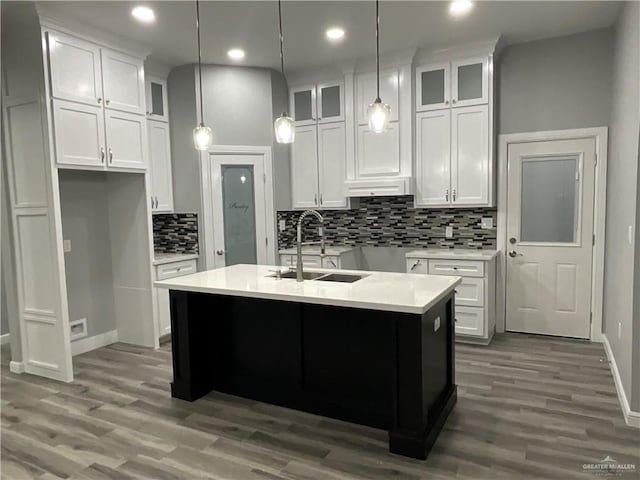 kitchen featuring baseboards, white cabinets, a sink, and wood finished floors