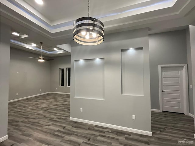 unfurnished room featuring baseboards, a tray ceiling, ceiling fan with notable chandelier, and dark wood-type flooring