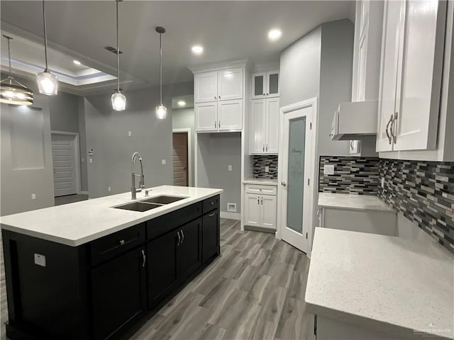 kitchen featuring dark cabinetry, tasteful backsplash, a sink, and white cabinets