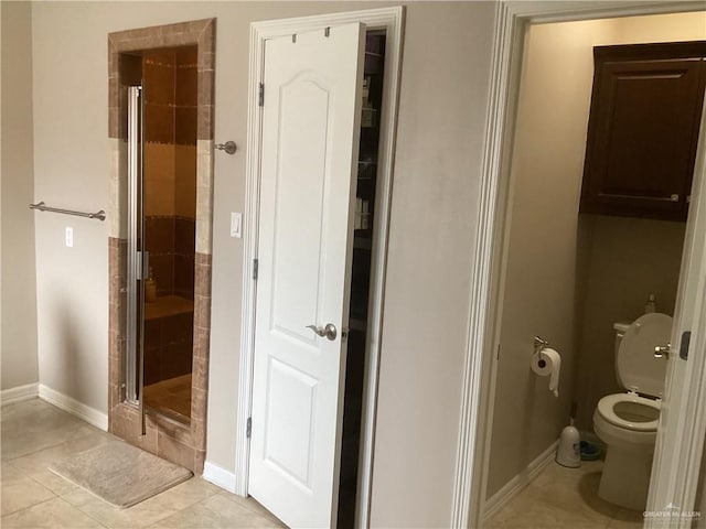 bathroom featuring toilet, an enclosed shower, and tile patterned flooring