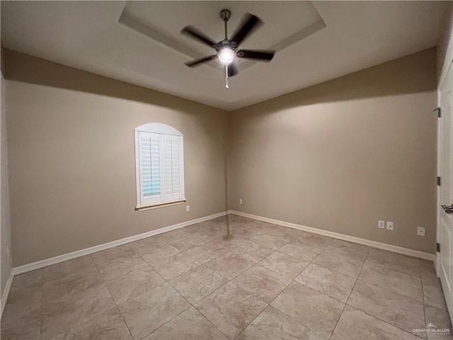 spare room featuring ceiling fan and a raised ceiling