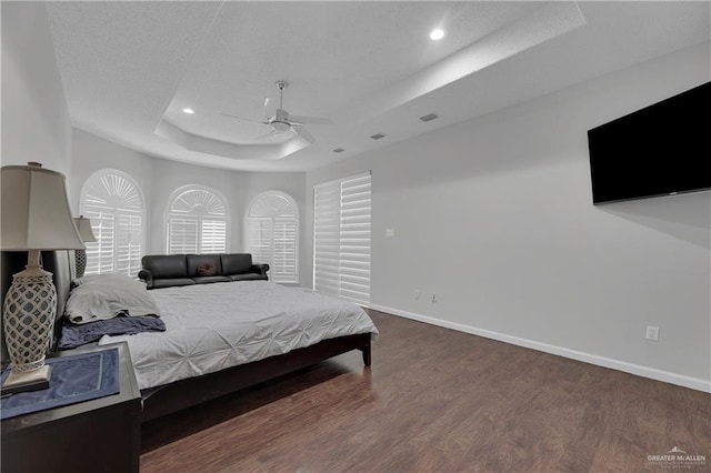 bedroom featuring a raised ceiling, ceiling fan, and dark wood-type flooring