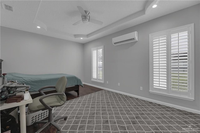 bedroom featuring a tray ceiling, ceiling fan, dark hardwood / wood-style floors, and a wall mounted air conditioner