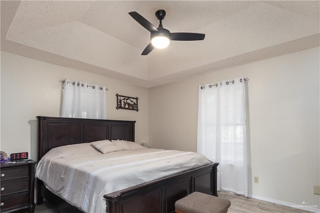 1309 El Camino Dr, Weslaco, TX 78599 - bedroom with light wood-style floors, baseboards, a ceiling fan, and a tray ceiling