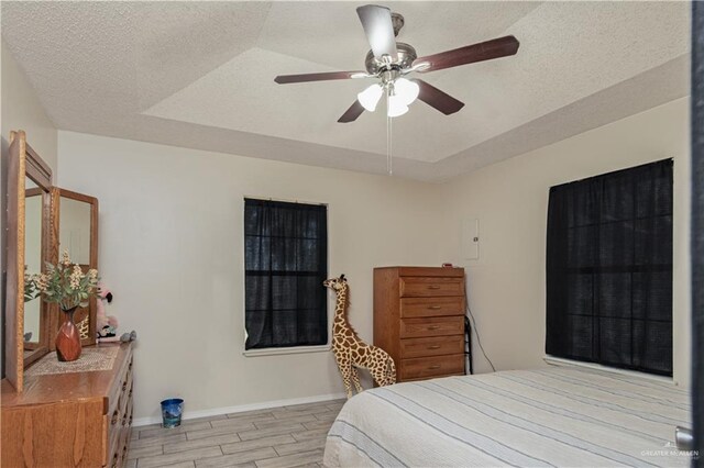 1309 El Camino Dr, Weslaco, TX 78599 - bedroom with a tray ceiling, wood finished floors, baseboards, a textured ceiling, and ceiling fan
