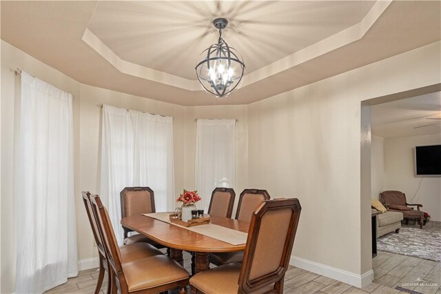 1309 El Camino Dr, Weslaco, TX 78599 - dining room featuring a tray ceiling, a chandelier, wood finish floors, and baseboards