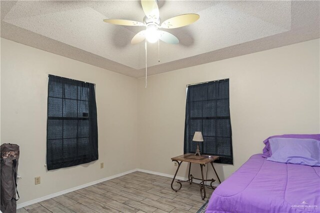 1309 El Camino Dr, Weslaco, TX 78599 - bedroom with light wood-style flooring, a textured ceiling, baseboards, and ceiling fan