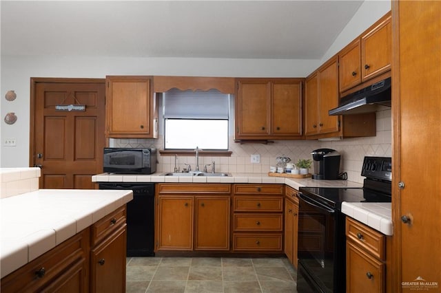 130 E Gardenia St, South Padre Island, TX 78597 - kitchen featuring tile countertops, brown cabinetry, black appliances, under cabinet range hood, and a sink