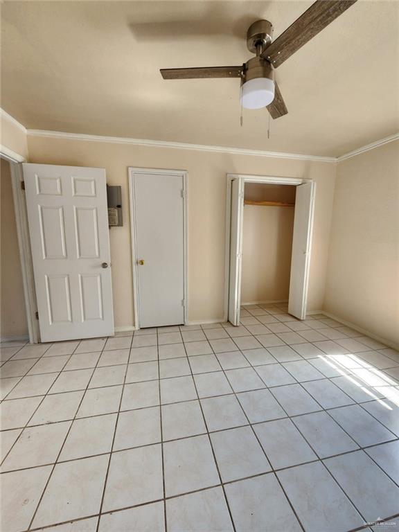 unfurnished bedroom featuring ceiling fan, crown molding, and light tile patterned floors