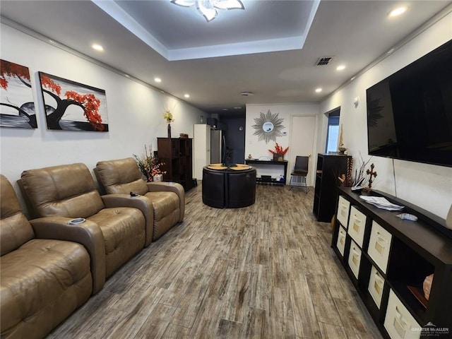 living room with wood-type flooring and a tray ceiling