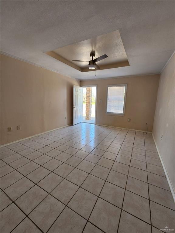 tiled spare room with a textured ceiling, a raised ceiling, ceiling fan, and ornamental molding