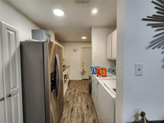 kitchen with washing machine and dryer, dark hardwood / wood-style floors, stainless steel fridge, white cabinets, and ornamental molding