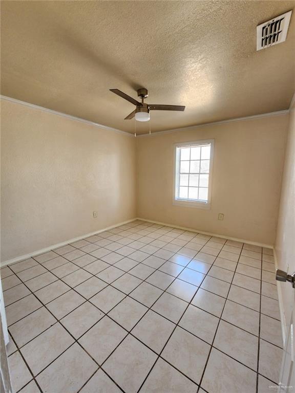 empty room with light tile patterned floors, a textured ceiling, ceiling fan, and ornamental molding