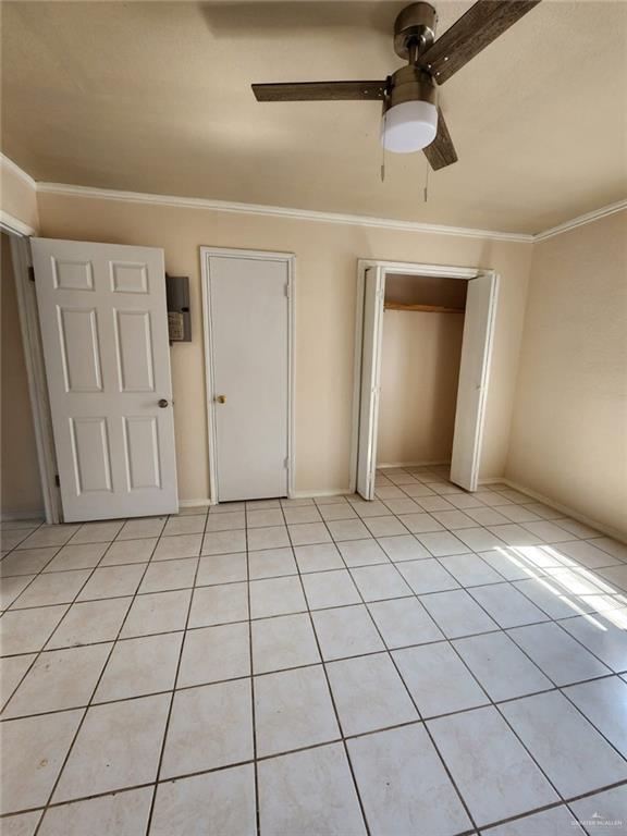 unfurnished bedroom featuring ceiling fan, crown molding, and light tile patterned flooring