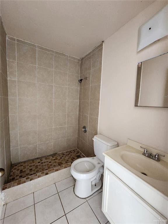 bathroom featuring tile patterned flooring, vanity, toilet, and a tile shower