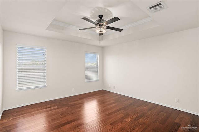 unfurnished room with a tray ceiling, ceiling fan, dark hardwood / wood-style floors, and ornamental molding