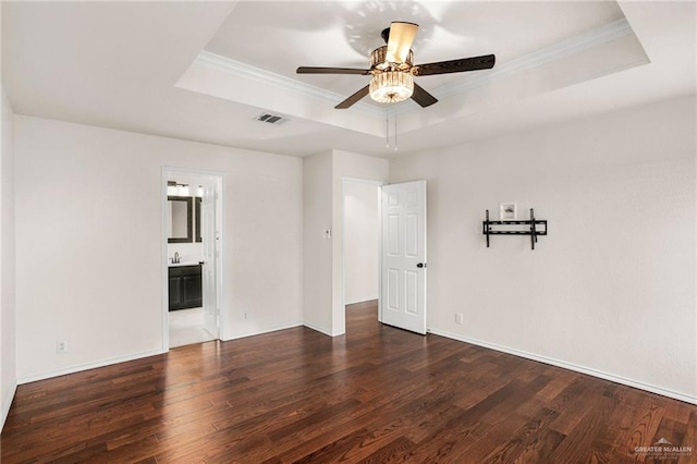 empty room featuring a tray ceiling, dark hardwood / wood-style floors, and ornamental molding