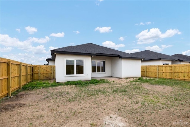 back of house with a fenced backyard and stucco siding