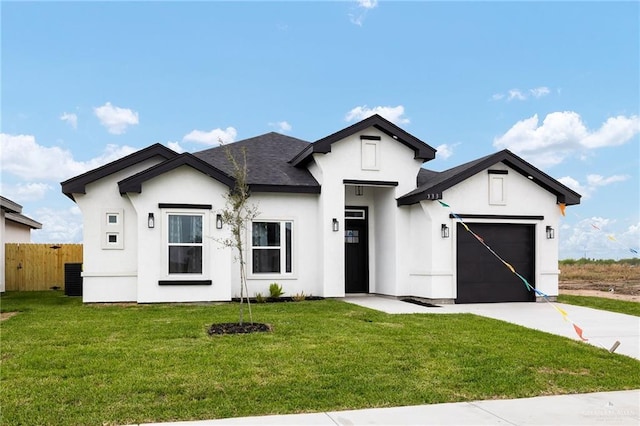 view of front of home with a front yard, fence, driveway, stucco siding, and a garage