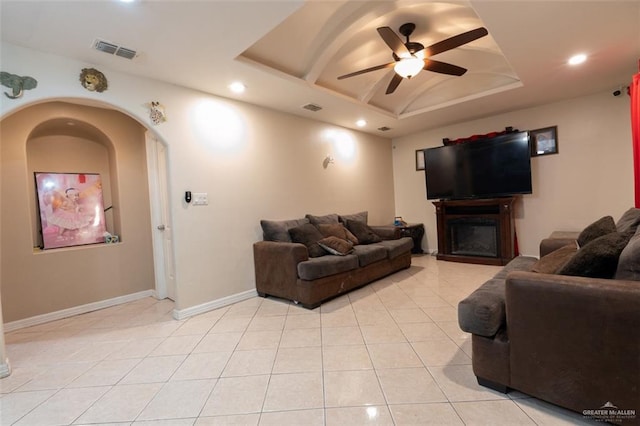 living room with a raised ceiling, ceiling fan, and light tile patterned floors