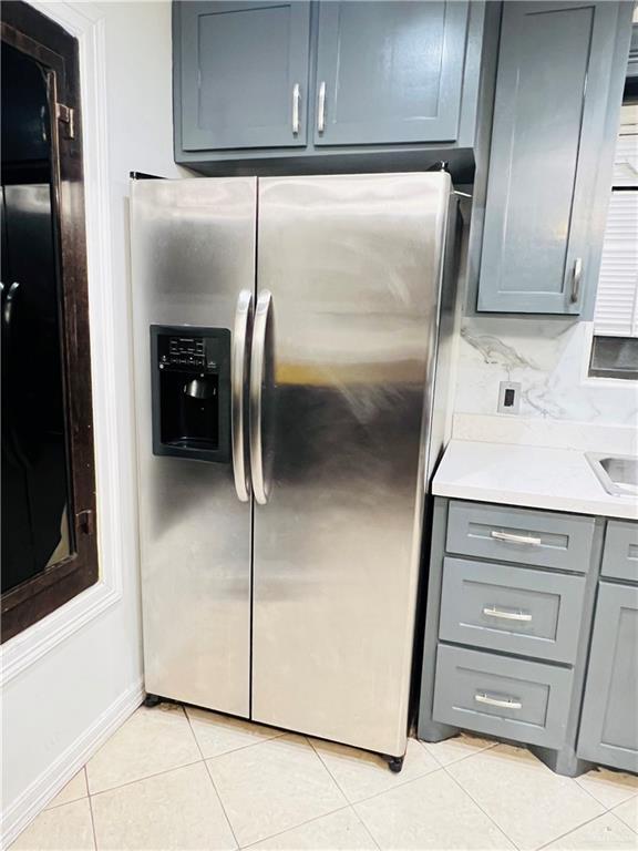 kitchen with tasteful backsplash, gray cabinetry, light tile patterned flooring, and stainless steel refrigerator with ice dispenser