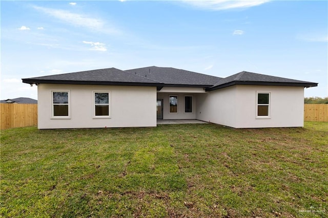 back of property featuring a patio, a yard, a shingled roof, stucco siding, and fence private yard