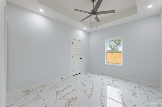 empty room with a tray ceiling, recessed lighting, a ceiling fan, and baseboards