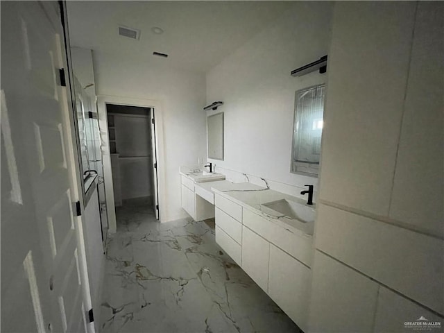 full bath featuring double vanity, visible vents, marble finish floor, and a sink