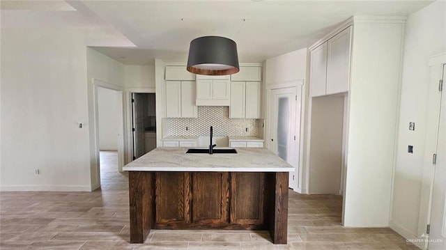 2721 Chesterfield Ave, Edinburg, TX 78539 - kitchen featuring a sink, light wood finished floors, a center island with sink, and backsplash
