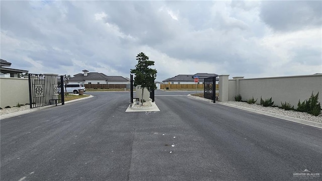 2721 Chesterfield Ave, Edinburg, TX 78539 - view of asphalt street with a gate, curbs, traffic signs, and a gated entry