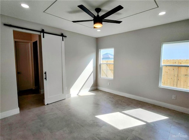 unfurnished room with a barn door, recessed lighting, a ceiling fan, and baseboards