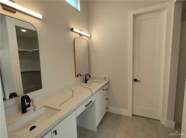 bathroom featuring a sink, baseboards, and double vanity