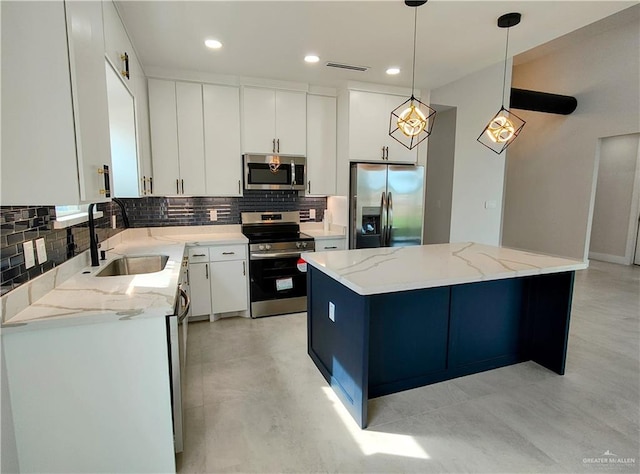 kitchen featuring visible vents, decorative backsplash, a kitchen island, stainless steel appliances, and a sink