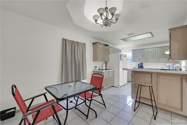 3019 Floresta St, Edinburg, TX 78541 - kitchen with freestanding refrigerator, tile counters, a chandelier, a peninsula, and light tile patterned floors