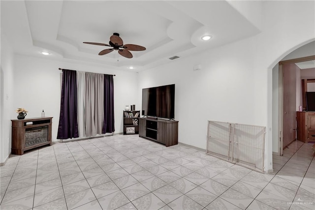 3019 Floresta St, Edinburg, TX 78541 - unfurnished living room featuring arched walkways, a ceiling fan, recessed lighting, and a tray ceiling