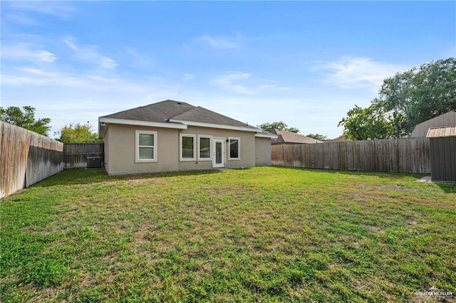 back of house with stucco siding, a yard, and a fenced backyard